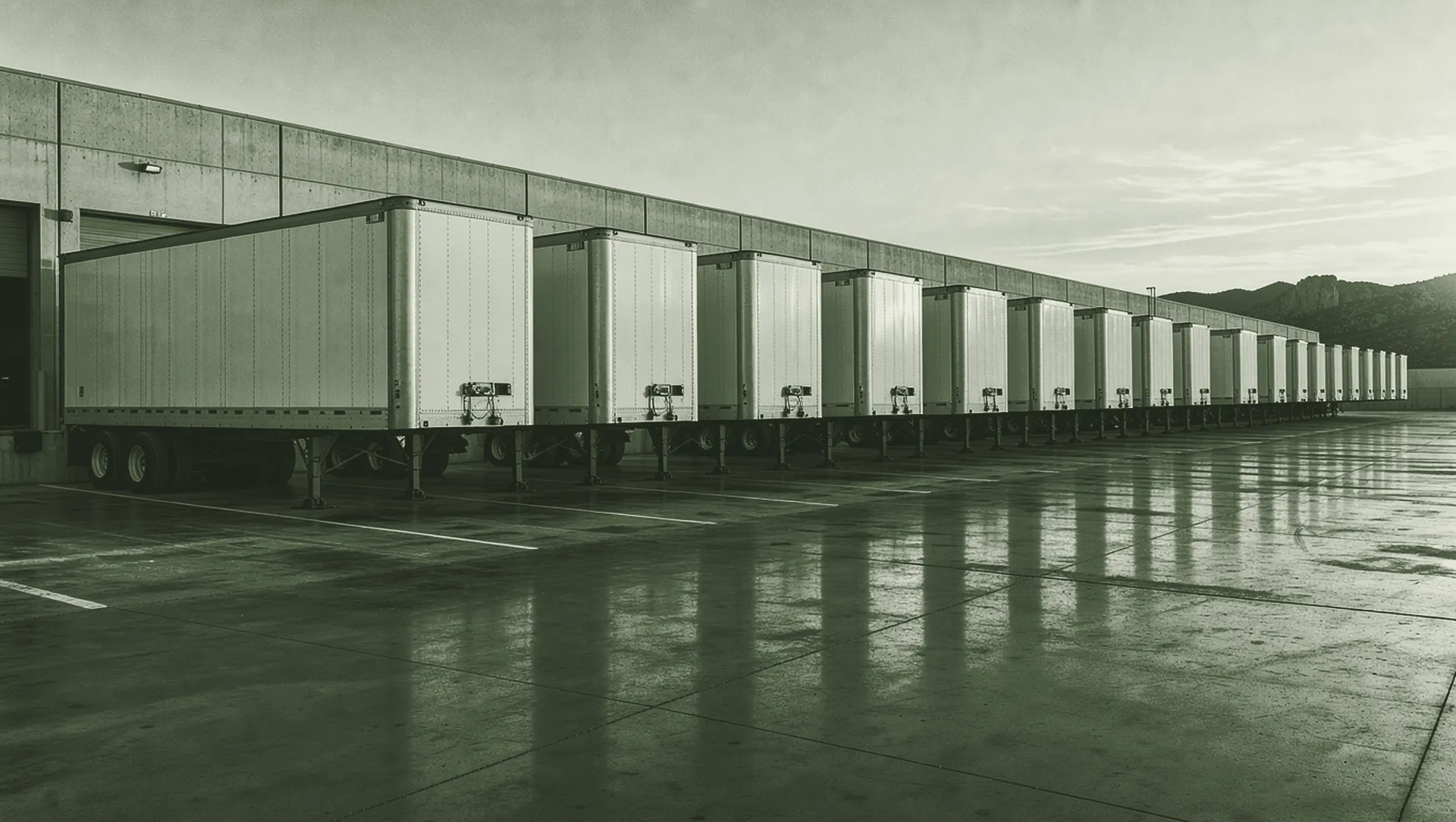 Patio de carga al amanecer con una fila de remolques en los andenes